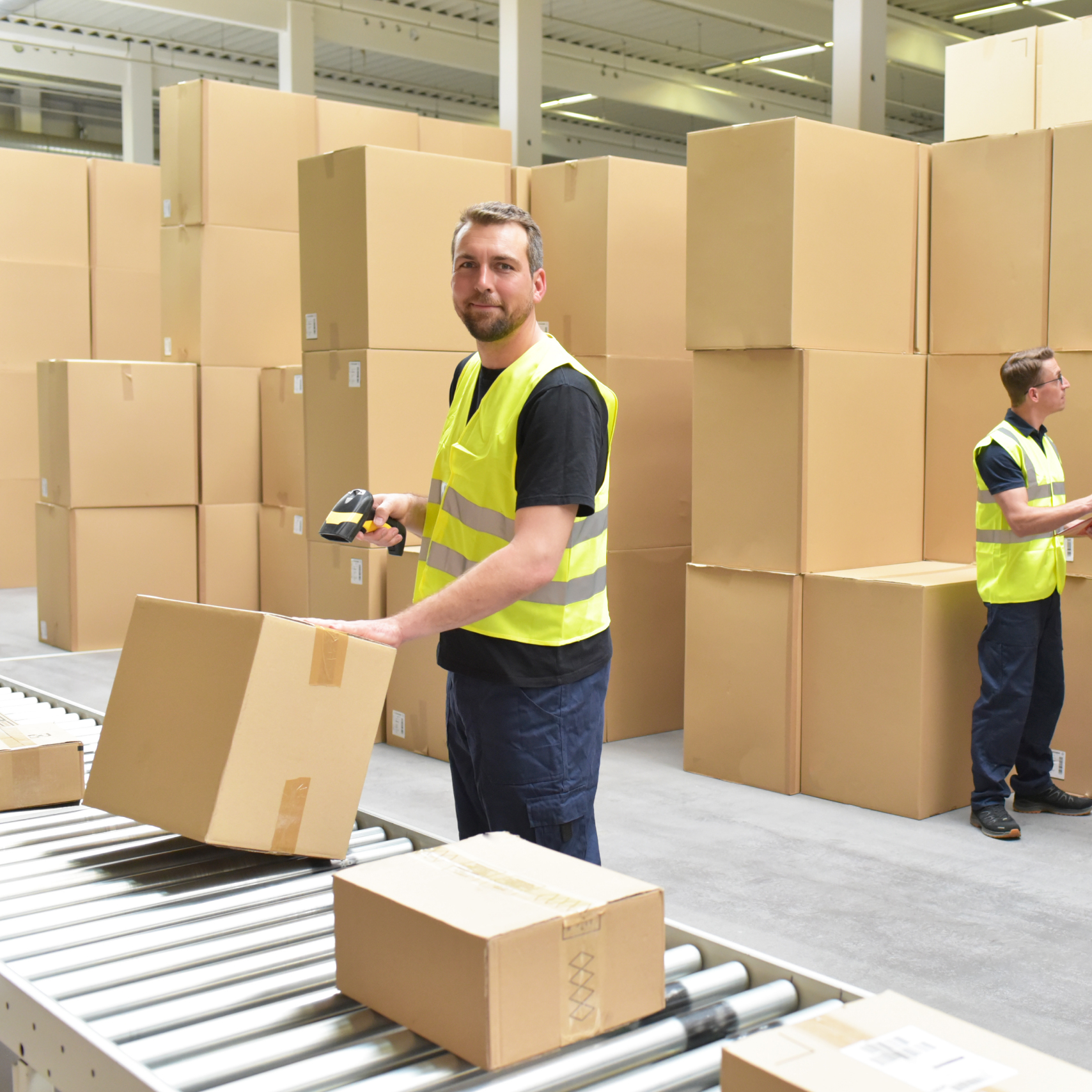 man in warehouse scanning parcels on a conveyor