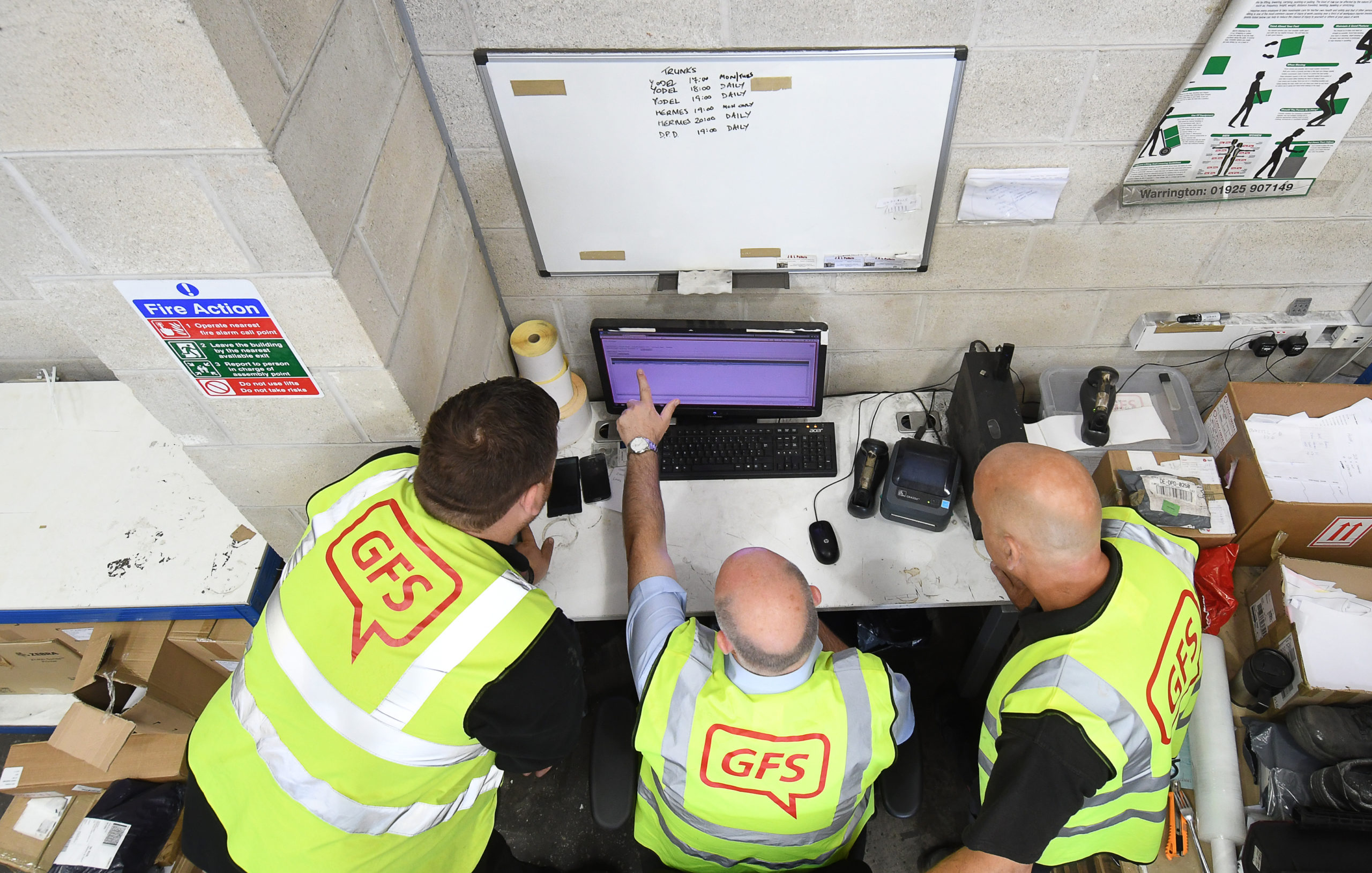 workers looking at a computer with high vis jackets on